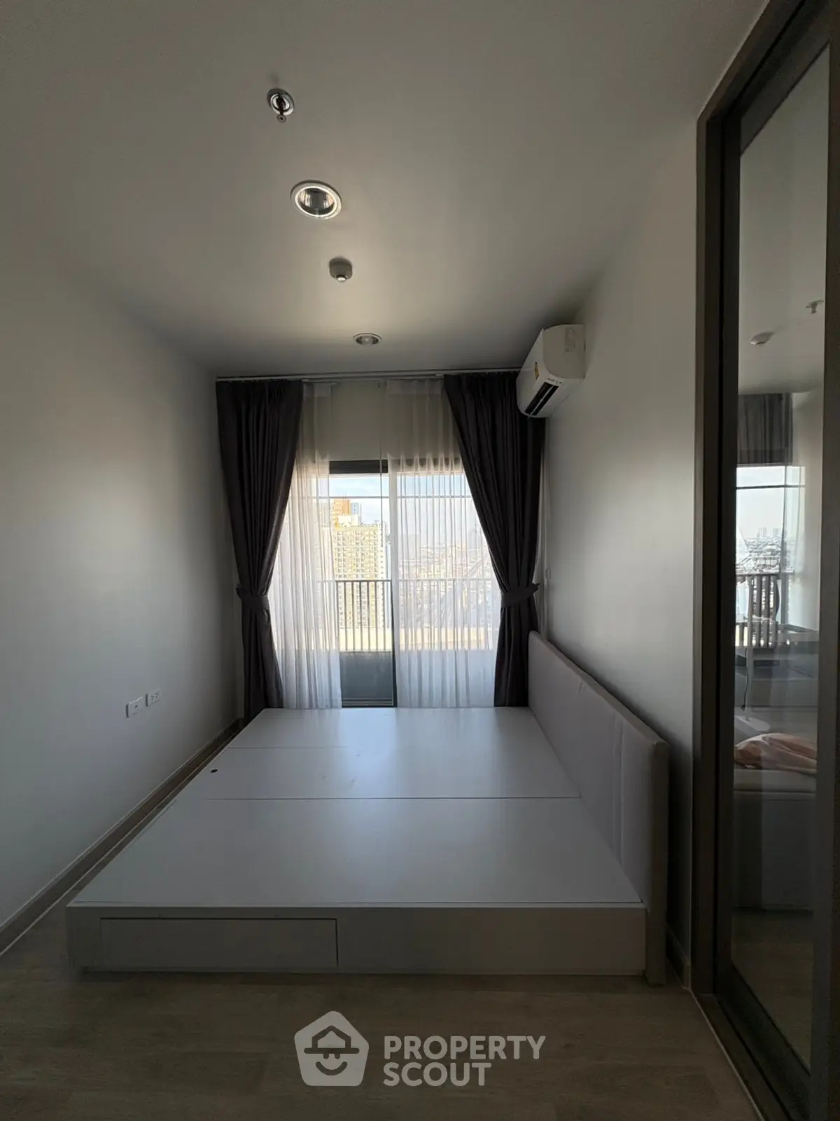 Modern bedroom with minimalist design and large window offering city view