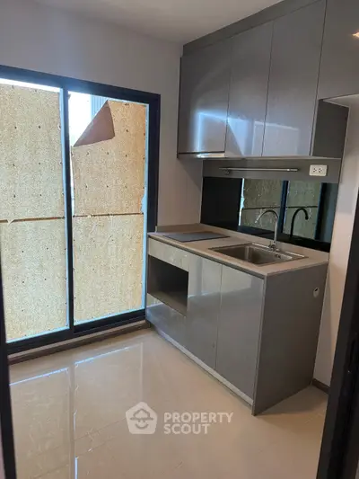 Modern kitchen with sleek cabinetry and large window, perfect for culinary enthusiasts.