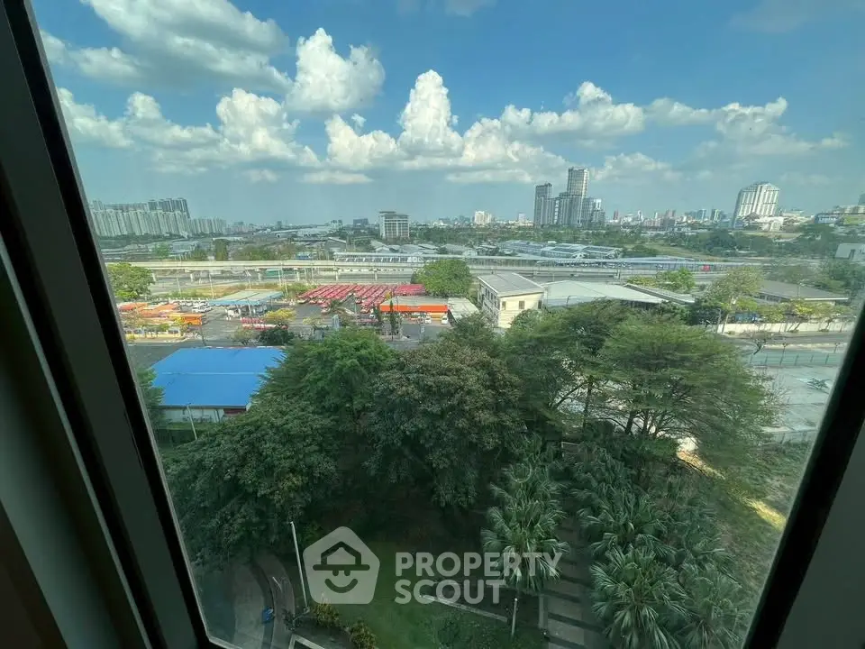 Stunning cityscape view from high-rise window overlooking lush greenery and urban skyline.