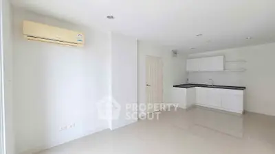 Modern minimalist kitchen with sleek white cabinets and air conditioning in a bright open space.