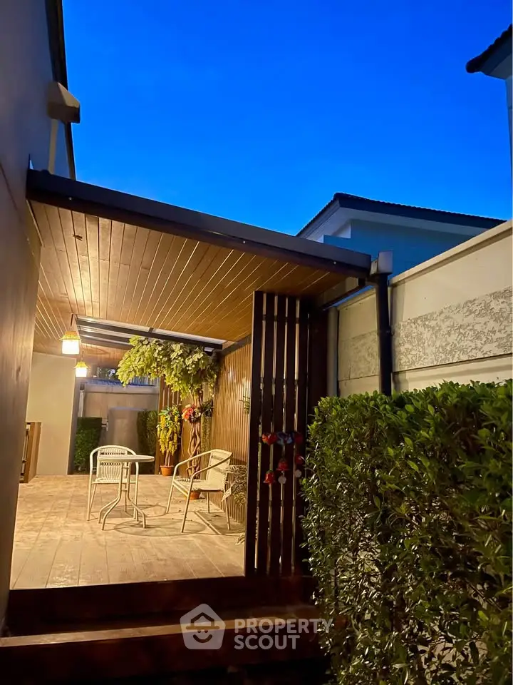 Charming outdoor patio with cozy seating and lush greenery, perfect for evening relaxation.