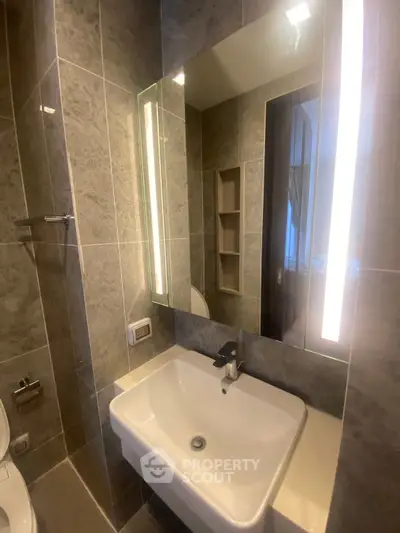 Modern bathroom with sleek sink and illuminated mirror in stylish apartment