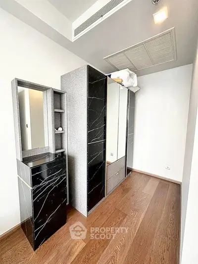 Modern bedroom with sleek black marble wardrobe and wooden flooring