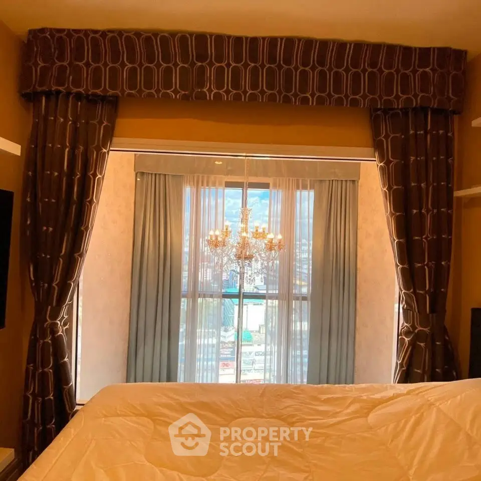 Luxurious bedroom with elegant drapes and stunning city view through large window.