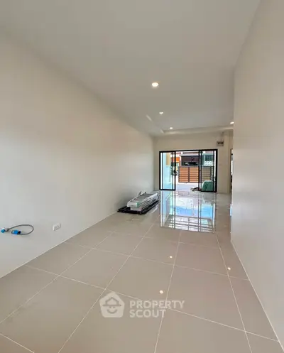 Spacious modern living room with glossy tiled floors and large sliding glass doors leading to a patio.