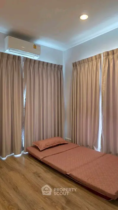 Cozy minimalist bedroom with floor mattress and air conditioning, perfect for a serene retreat.