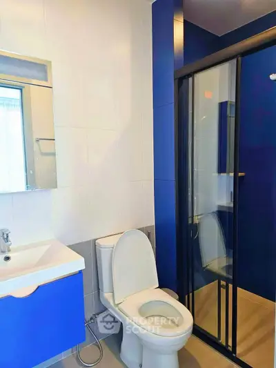 Modern bathroom with blue accents, featuring a sleek shower and contemporary fixtures.