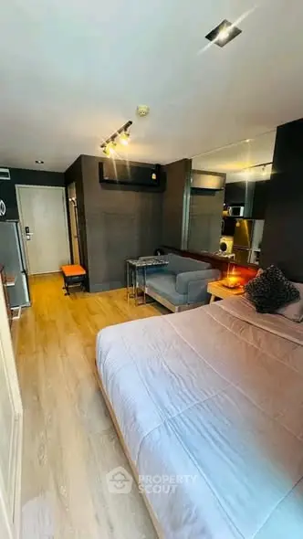 Modern studio apartment with cozy bedroom and stylish living area, featuring sleek wooden flooring and contemporary decor.