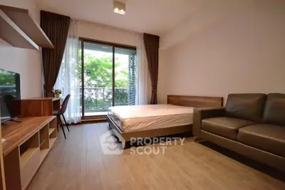 Modern bedroom with balcony view, featuring sleek furniture and natural light.