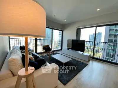 Modern living room with large windows and city view, featuring sleek furniture and natural light.