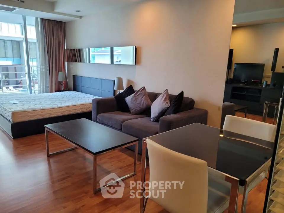 Modern studio apartment with cozy living area and stylish furnishings, featuring a comfortable bed and sleek dining space.