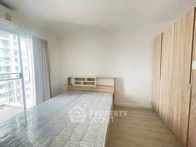 Modern bedroom with large window and wooden wardrobe in a high-rise apartment