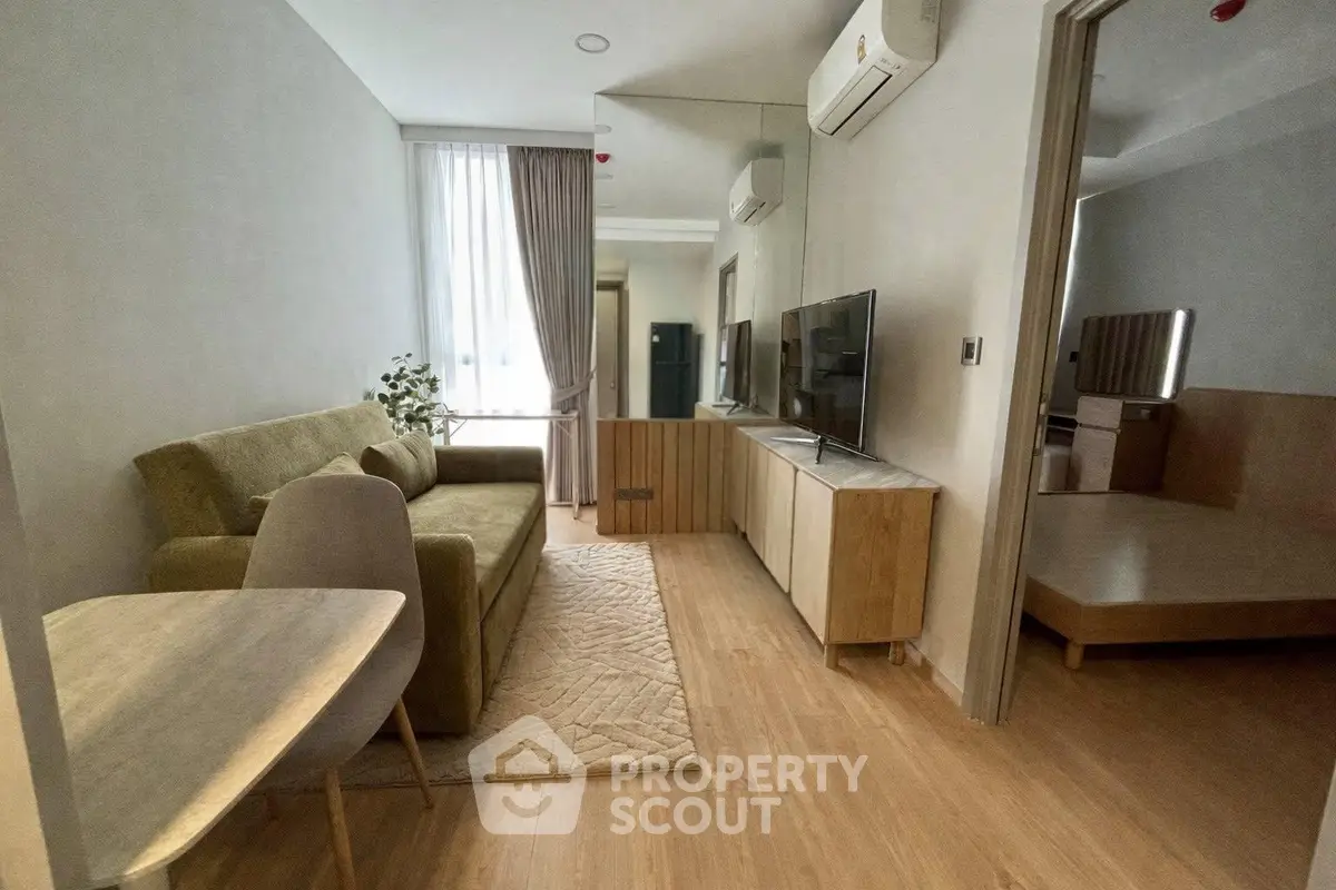 Modern living room with stylish furniture and natural light, adjacent to a cozy bedroom.