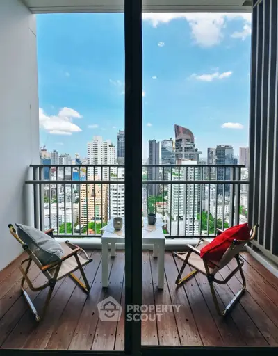 Stunning city view from a modern balcony with cozy seating, perfect for relaxation.