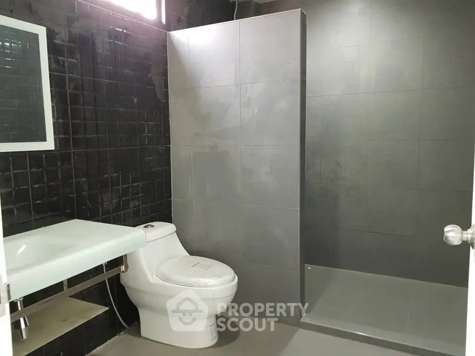 Modern bathroom with sleek black tiles and spacious shower area.