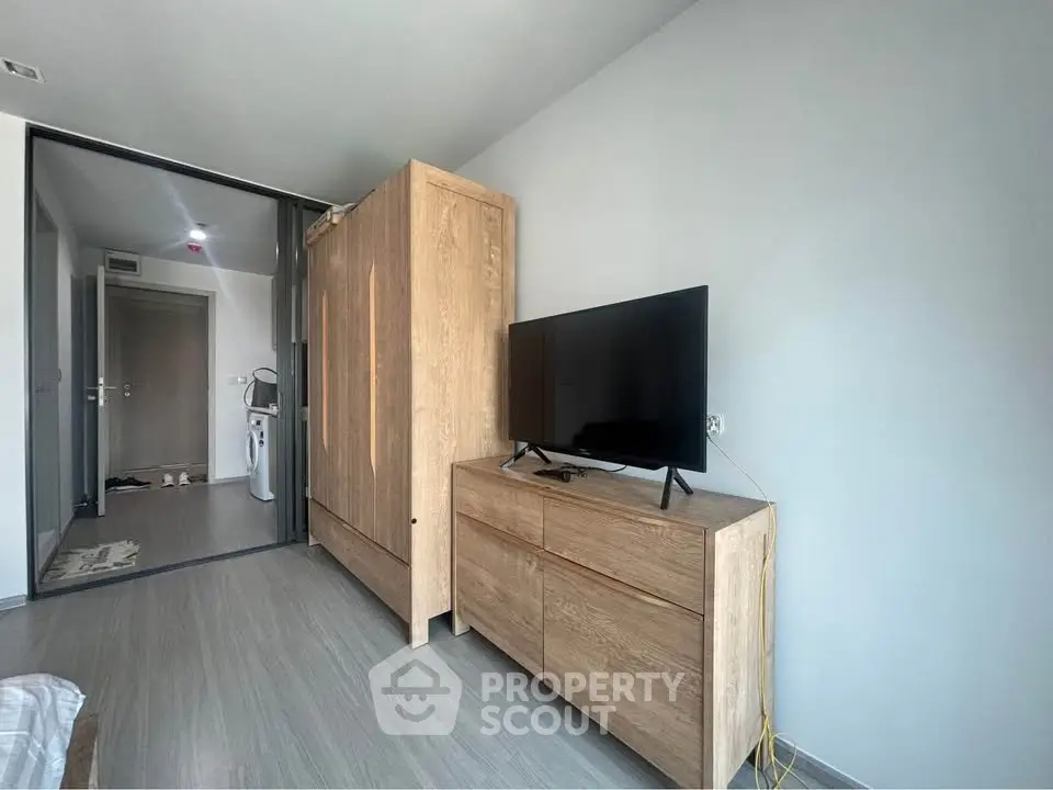 Modern apartment interior with sleek wooden furniture and flat-screen TV, showcasing minimalist design.