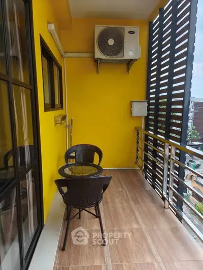 Charming balcony with seating and vibrant yellow walls, perfect for relaxation.