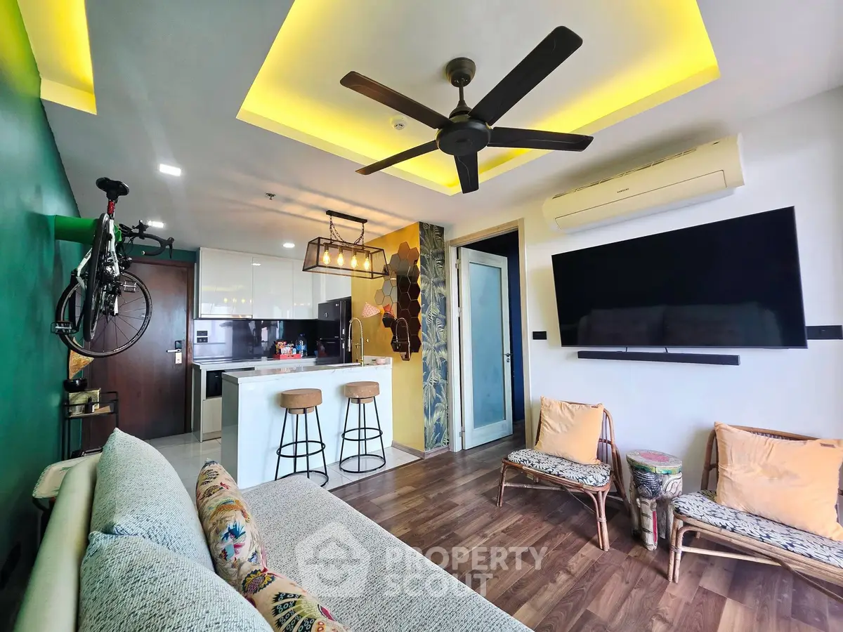 Modern living room with stylish decor, ceiling fan, and open kitchen layout, perfect for urban living.