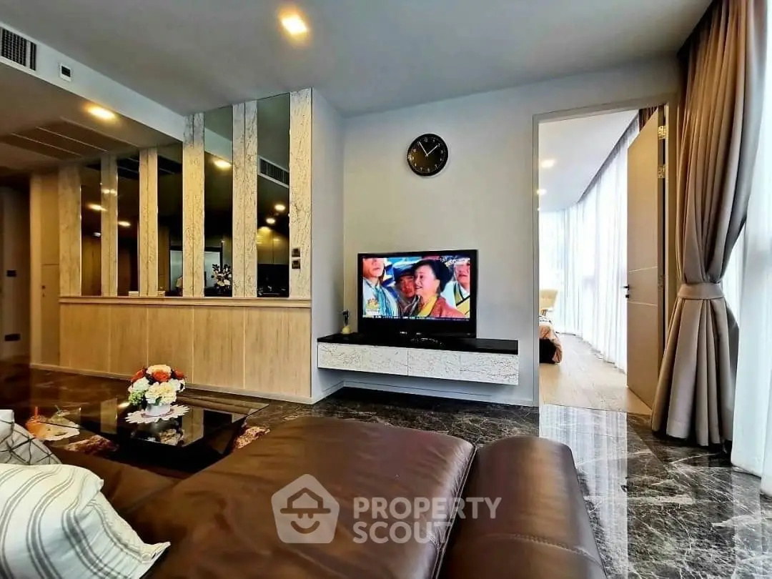 Luxurious living room with modern decor and marble flooring, featuring a cozy seating area and wall-mounted TV.