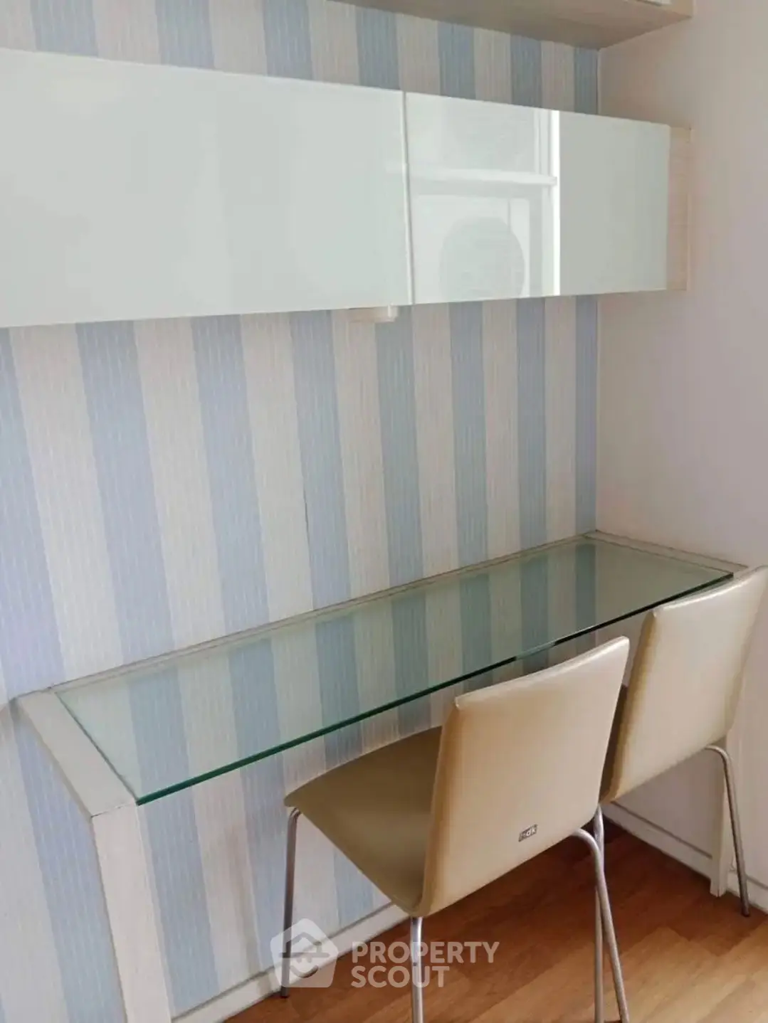 Modern study area with glass desk and sleek chairs in stylish apartment.