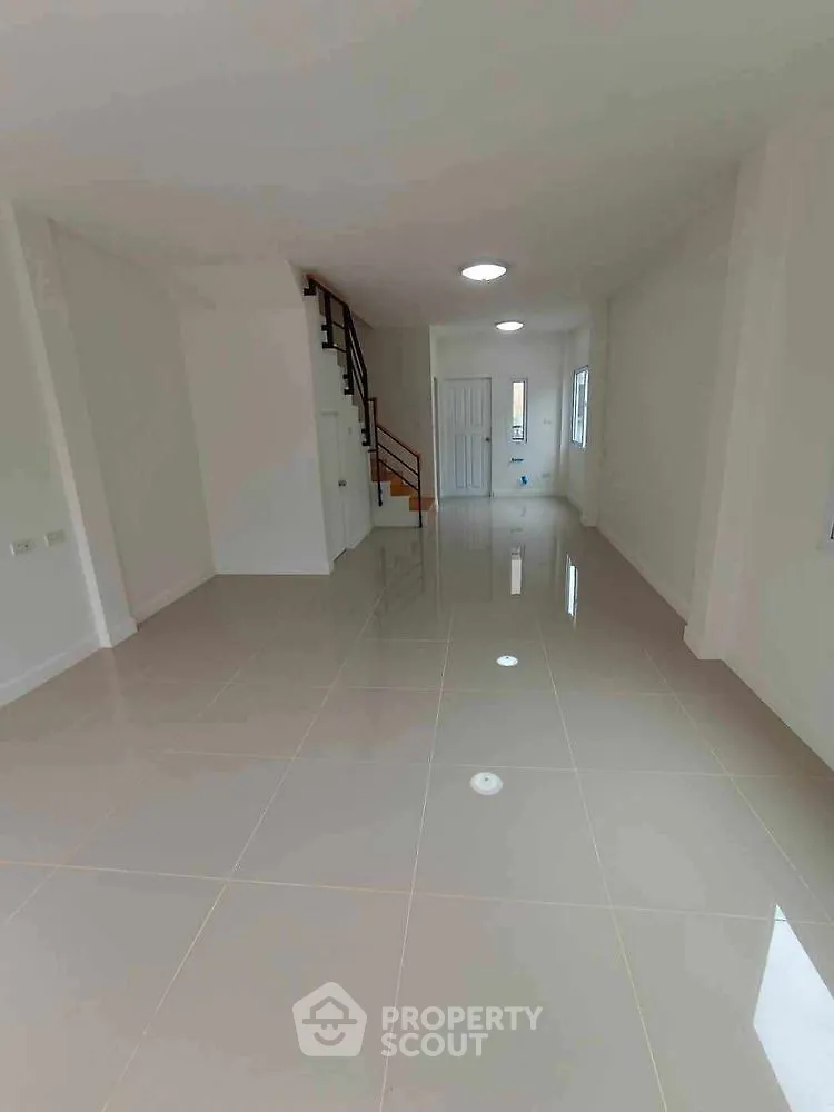 Spacious open-plan living area with glossy tiled floors and staircase.