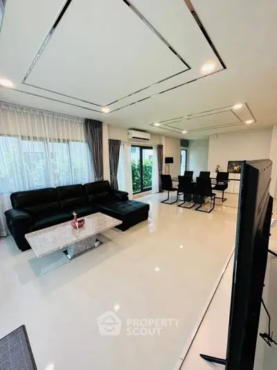 Spacious modern living room with sleek black furniture and large windows for natural light.