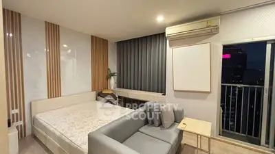 Modern bedroom with stylish decor and city view balcony, featuring a cozy bed and sleek furniture.