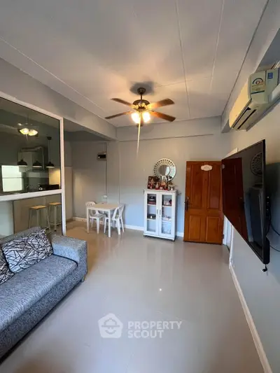 Modern living room with ceiling fan, wall-mounted TV, and cozy seating area.