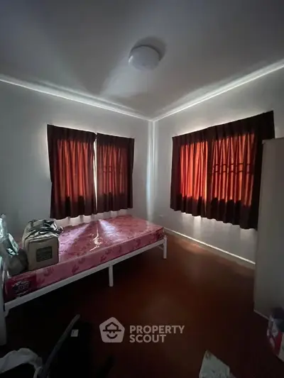 Cozy bedroom with natural light, featuring a simple bed and warm curtains, perfect for a restful retreat.