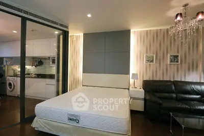 Modern bedroom with glass partition, stylish lighting, and adjacent kitchen area.