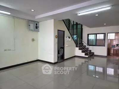 Spacious open-plan living area with staircase and tiled flooring in modern home.