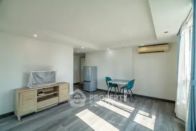 Bright modern living room with dining area and air conditioning, featuring sleek flooring and natural light.