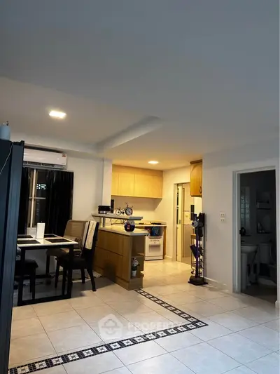 Modern open-layout kitchen and dining area with stylish lighting and tiled flooring.