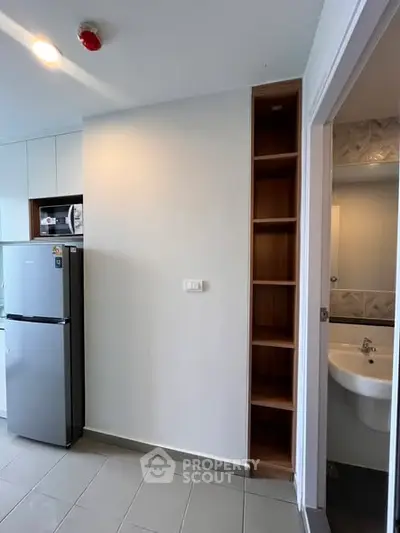 Modern kitchen with sleek appliances and adjacent bathroom in a compact apartment.