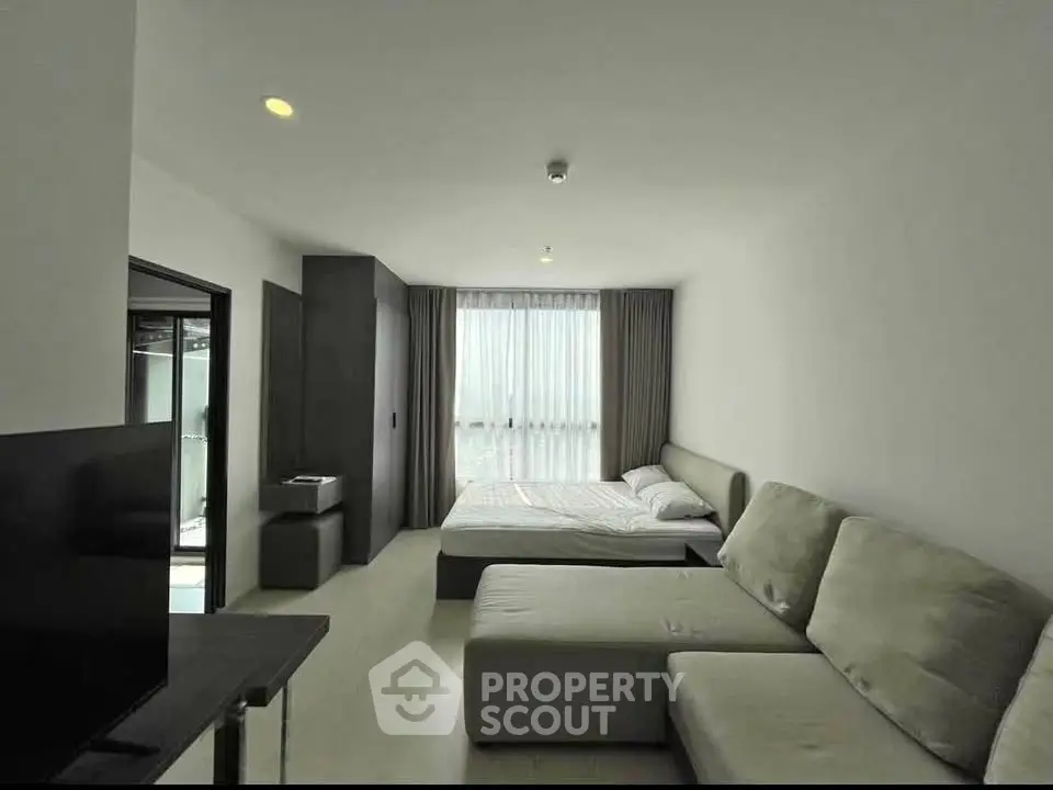 Modern studio apartment with cozy living area and large window for natural light.