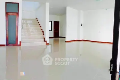 Spacious modern living room with glossy tiled floors and staircase