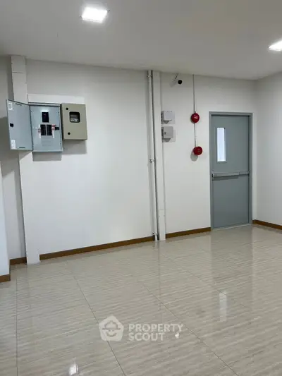 Spacious utility room with tiled flooring and electrical panels, ideal for storage or maintenance use.