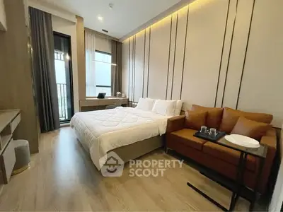 Modern bedroom with cozy bed, stylish sofa, and balcony access in a chic apartment.