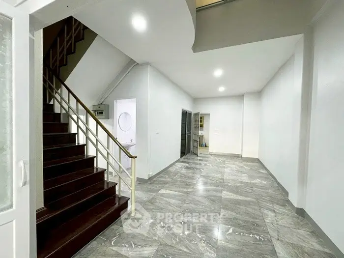 Spacious modern hallway with elegant staircase and marble flooring