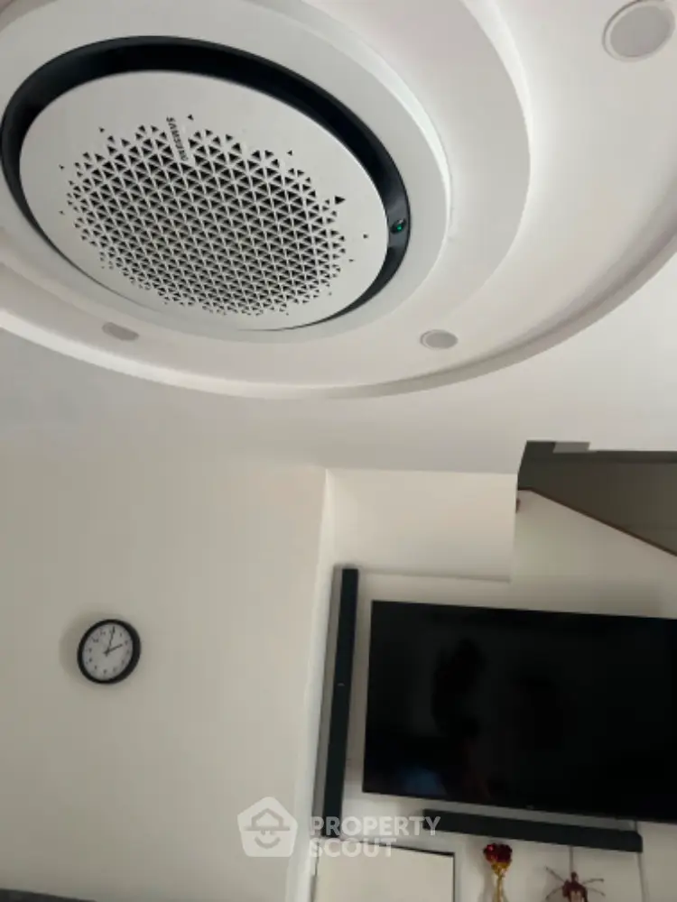 Modern living room with stylish ceiling speaker and wall-mounted TV