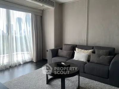 Modern living room with sleek gray sofa and city view through large windows.