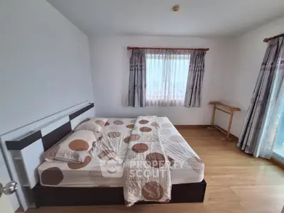 Spacious bedroom with modern decor and large window for natural light.