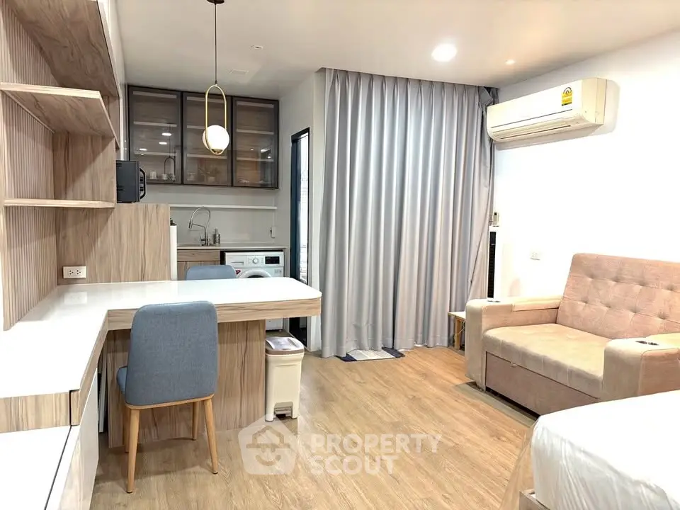 Modern studio apartment with open kitchen and cozy living area, featuring stylish furniture and wooden flooring.