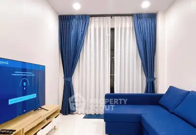 Modern living room with blue sofa and curtains, featuring a sleek TV setup.
