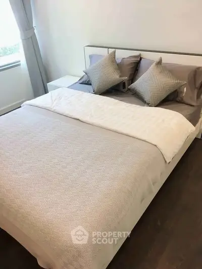 Cozy bedroom with stylish bedding and natural light, perfect for relaxation.