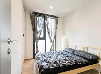 Modern bedroom with stylish decor and natural light, featuring a cozy bed and elegant curtains.