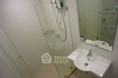 Modern bathroom with glass shower and sleek white sink in a contemporary apartment.