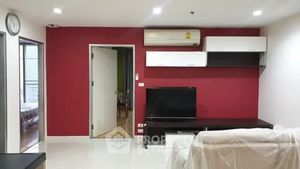 Modern living room with red accent wall, air conditioning, and sleek furniture in a stylish apartment.