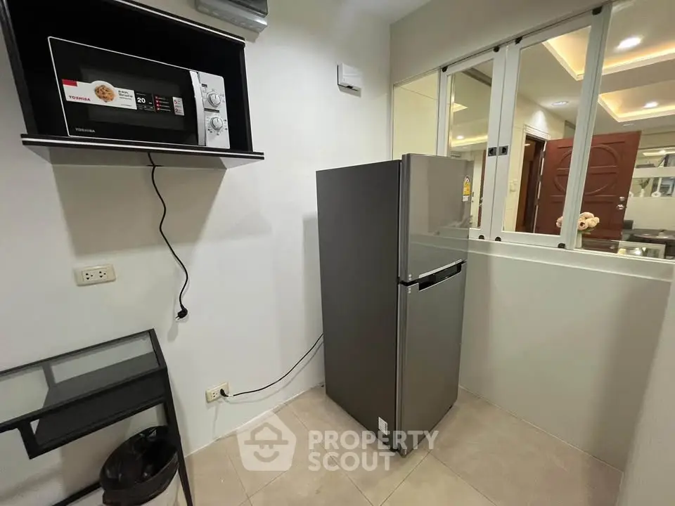 Modern kitchen with sleek fridge and microwave in compact space