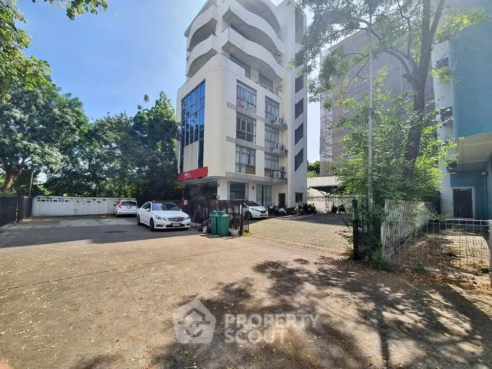 Modern multi-story building with spacious parking and lush greenery